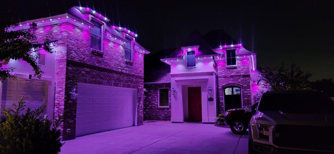 A house illuminated with vibrant purple lights at night